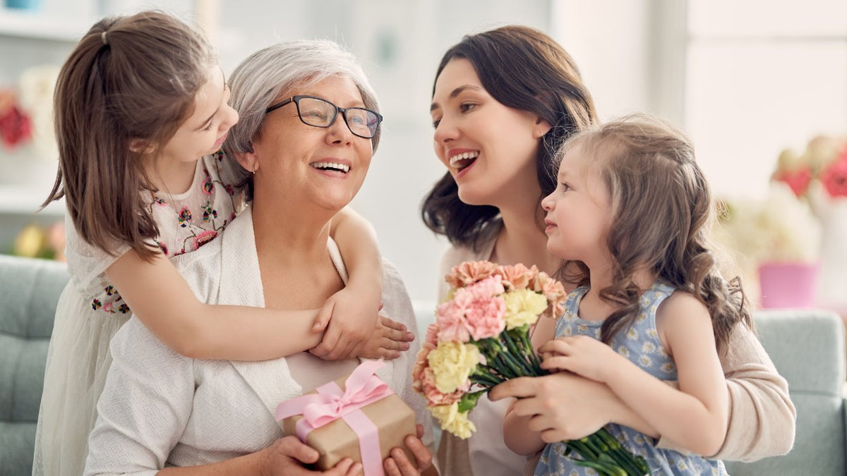 Eine Familie überreicht Mama Blumen und ein Geschenk