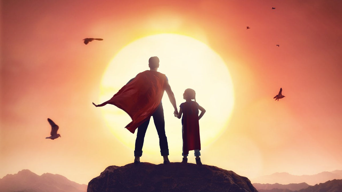 Father and child as superheroes in the sunset